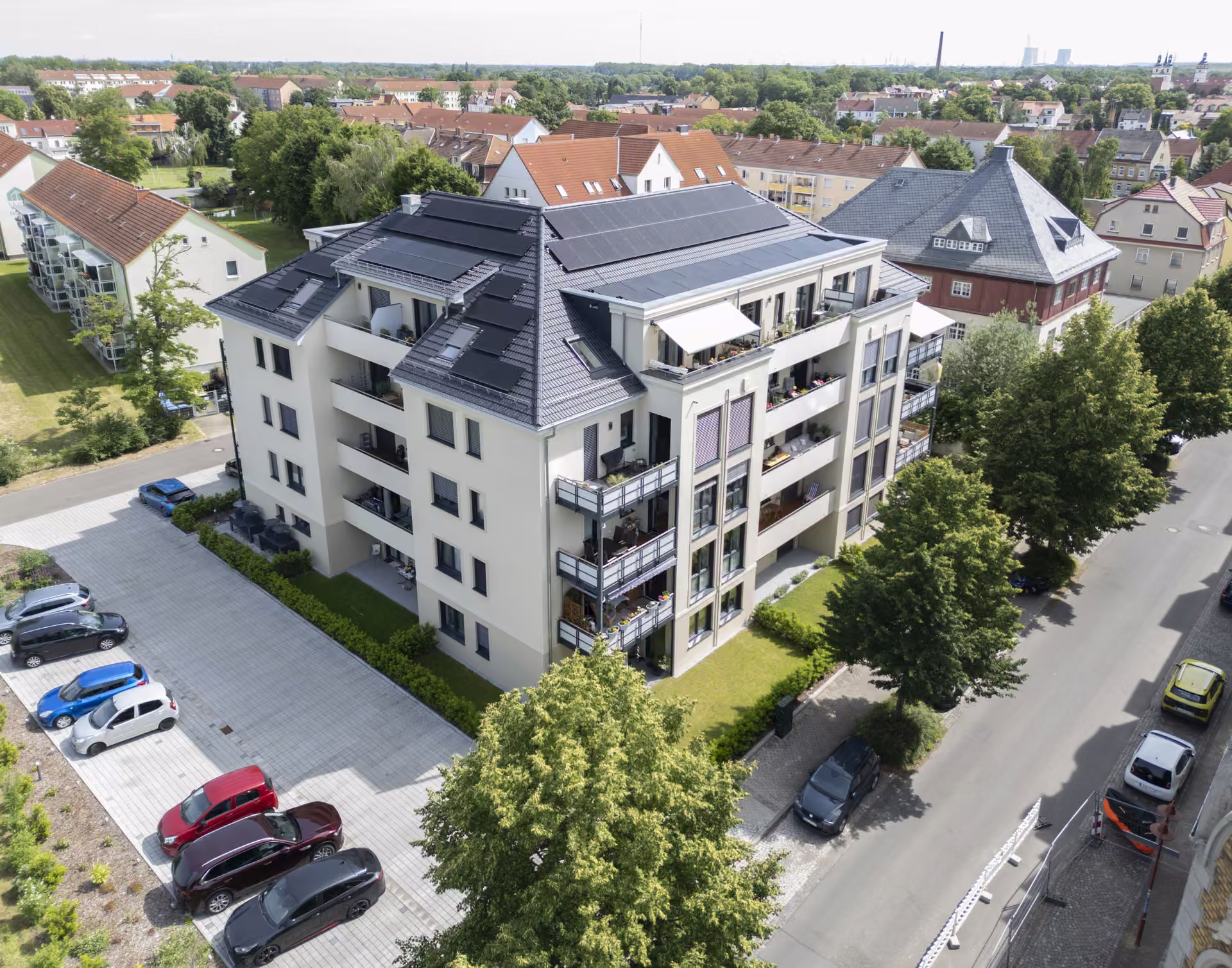 Luftbild des Torhauses mit Dachterrasse und Markise, dahinter die Dächer der umliegenden Stadtbebauung bis zum Horizont.