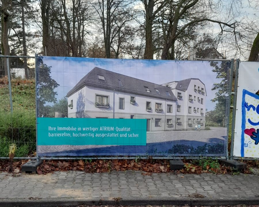 Bauzaun mit befestigter Visualisierung des geplanten Wohngebäudes