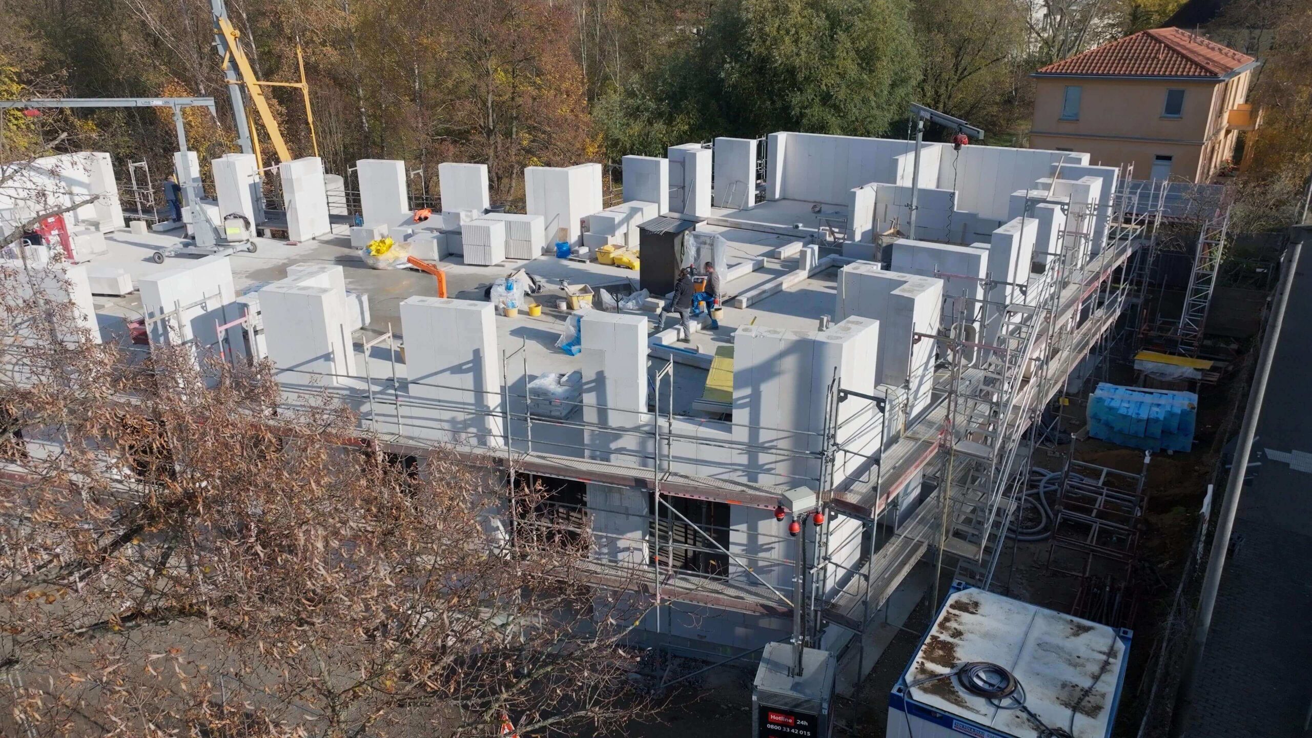 Rohbau eines Gebäudes mit fertiggestelltem Erdgeschoss und laufenden Mauerwerksarbeiten im 1. Obergeschoss