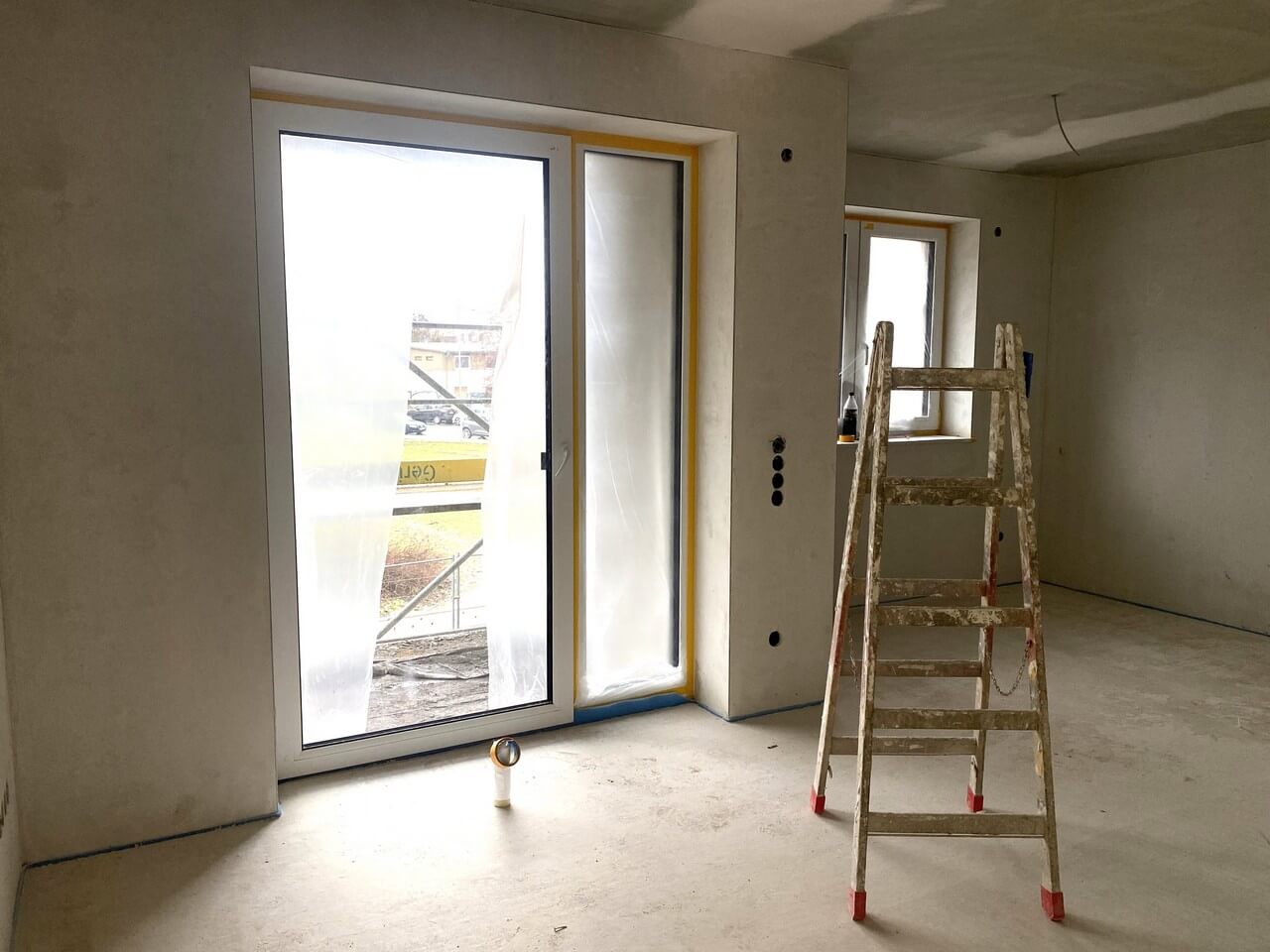 Neubauwohnung mit frisch gegossenem Estrich und verputzten Innenwänden im Rohbauzustand