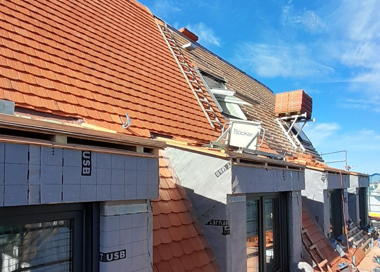 Dach eines Neubaus mit roten Dachziegeln, Dachfenster und Materialtransport per Bauaufzug